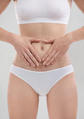 Buy stock photo Woman, hands and stomach for wellness in studio, heart and body for diet and holistic gut health. Digestion, weight loss and abdomen detox for female person, self care for balance on background