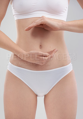 Buy stock photo Cropped shot of a young woman using her hands to frame her stomach