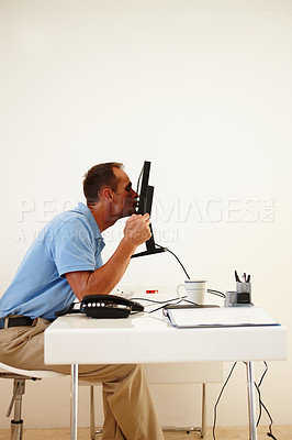 Buy stock photo A middle-aged man ethusiastically kissing his computer screen while sitting at his desk