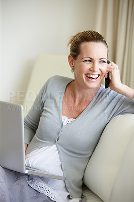 Buy stock photo A happy young woman talking on her cellphone while sitting with her laptop