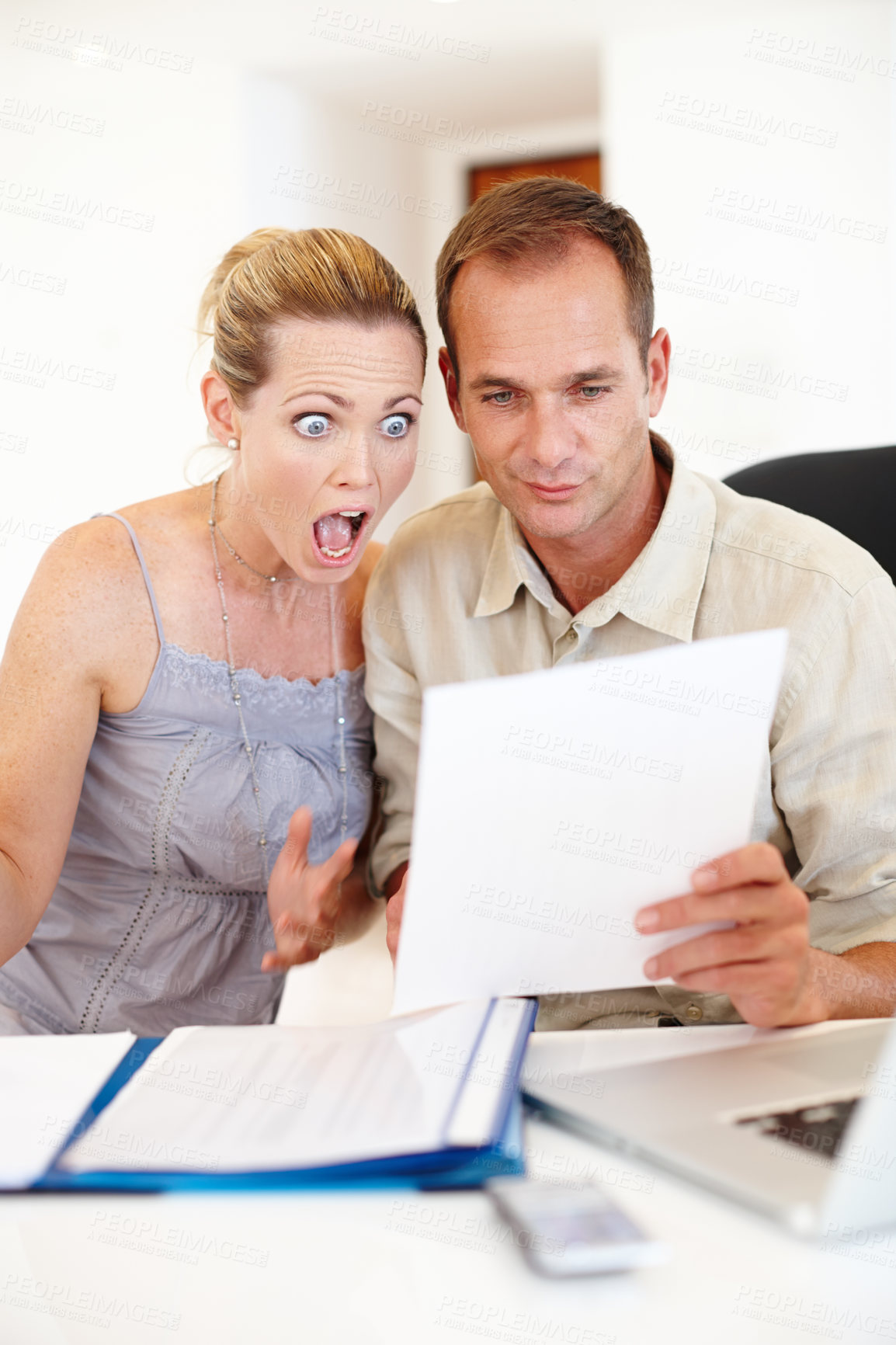 Buy stock photo Shot of a couple looking at paperwork with a laptop in front of them