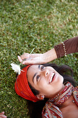 Buy stock photo Woman, smile and flower outdoor for gypsy with plant in nature for summer and adventure in garden. Young person, lady or boho and lay on grass for bohemian style, fun and free spirit in spring