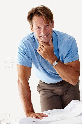 Buy stock photo Shot of a smiling man standing over a set of plans on a table