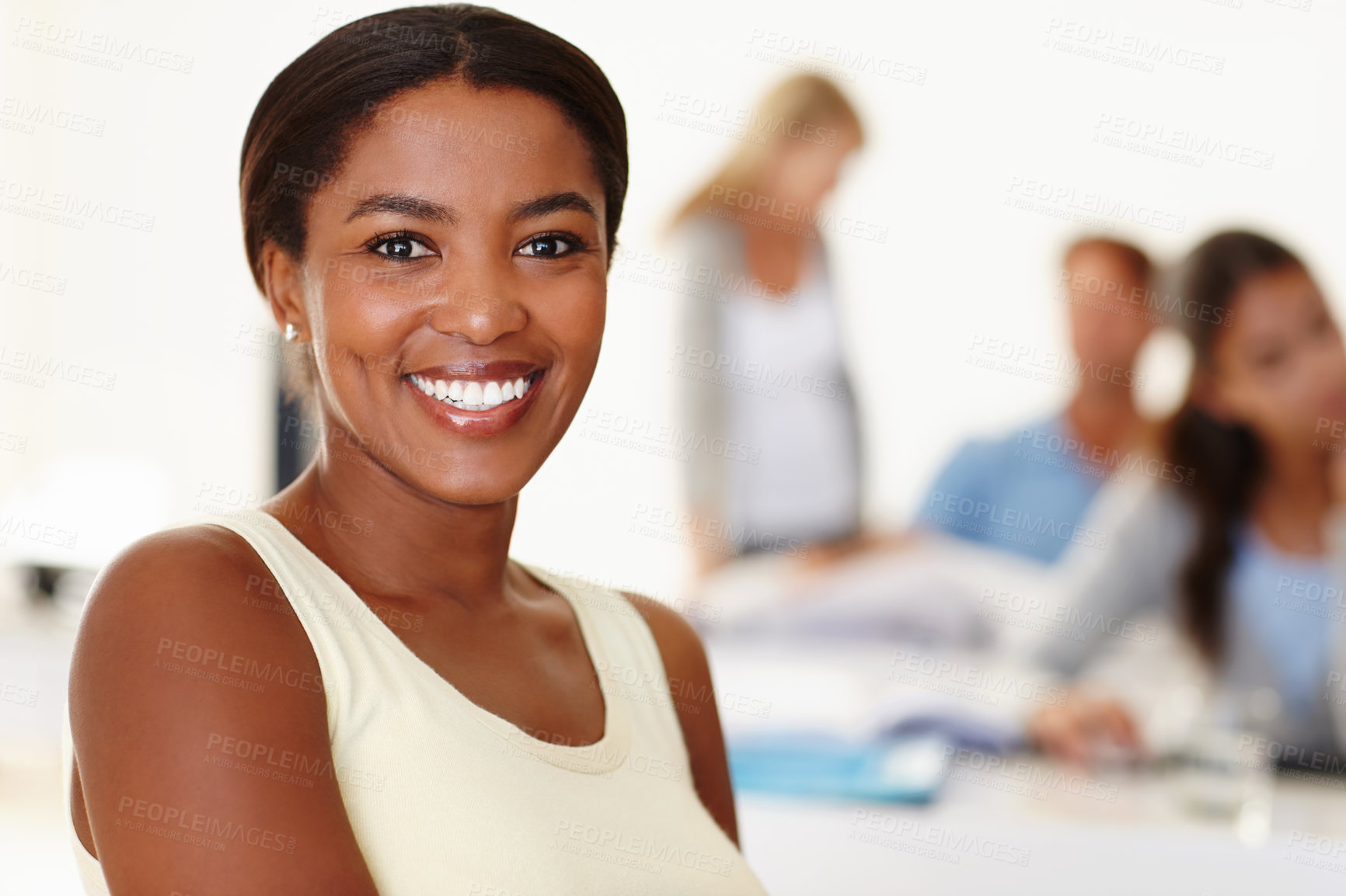 Buy stock photo Portrait of creative businesswoman sitting in the office with her colleagues in the background. Smiling entrepreneur and designer feeling confident in workplace. Black professional feeling successful