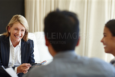 Buy stock photo Shot of a smiling woman using a calculator in a seated meeting