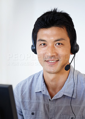 Buy stock photo Portrait of an Asian man using a headset while sitting at a computer