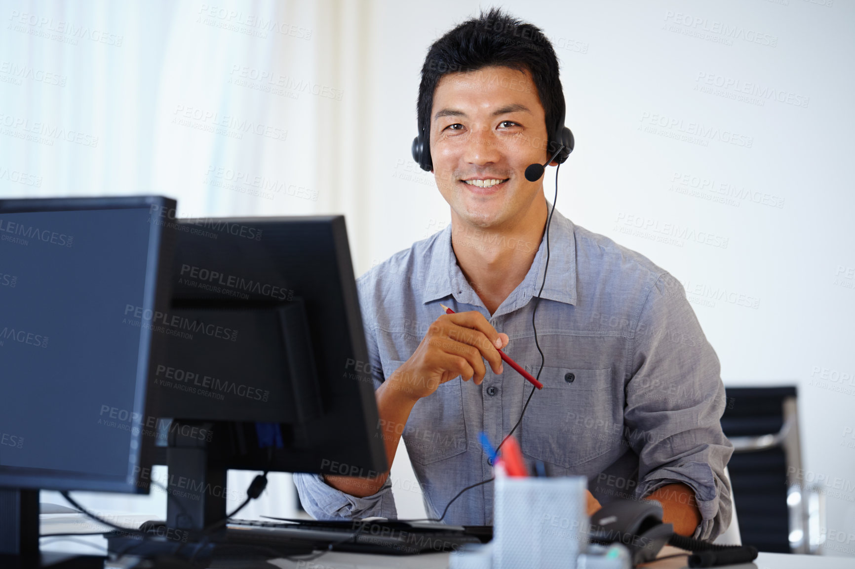 Buy stock photo Shot of an Asian man using a computer and talking on a headset