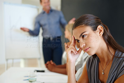 Buy stock photo Young businesswoman looking bored in a meeting her with hand on her temple