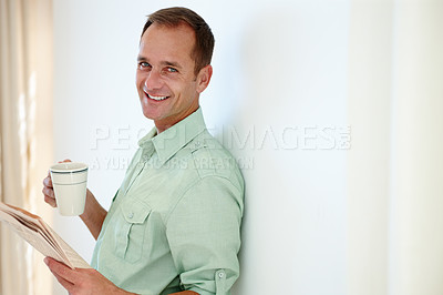 Buy stock photo Man, newspaper and morning coffee in home, reading news articles and headlines for information and standing. Happy, smile male person and relaxed with beverage in cup, lounge in apartment for comfort