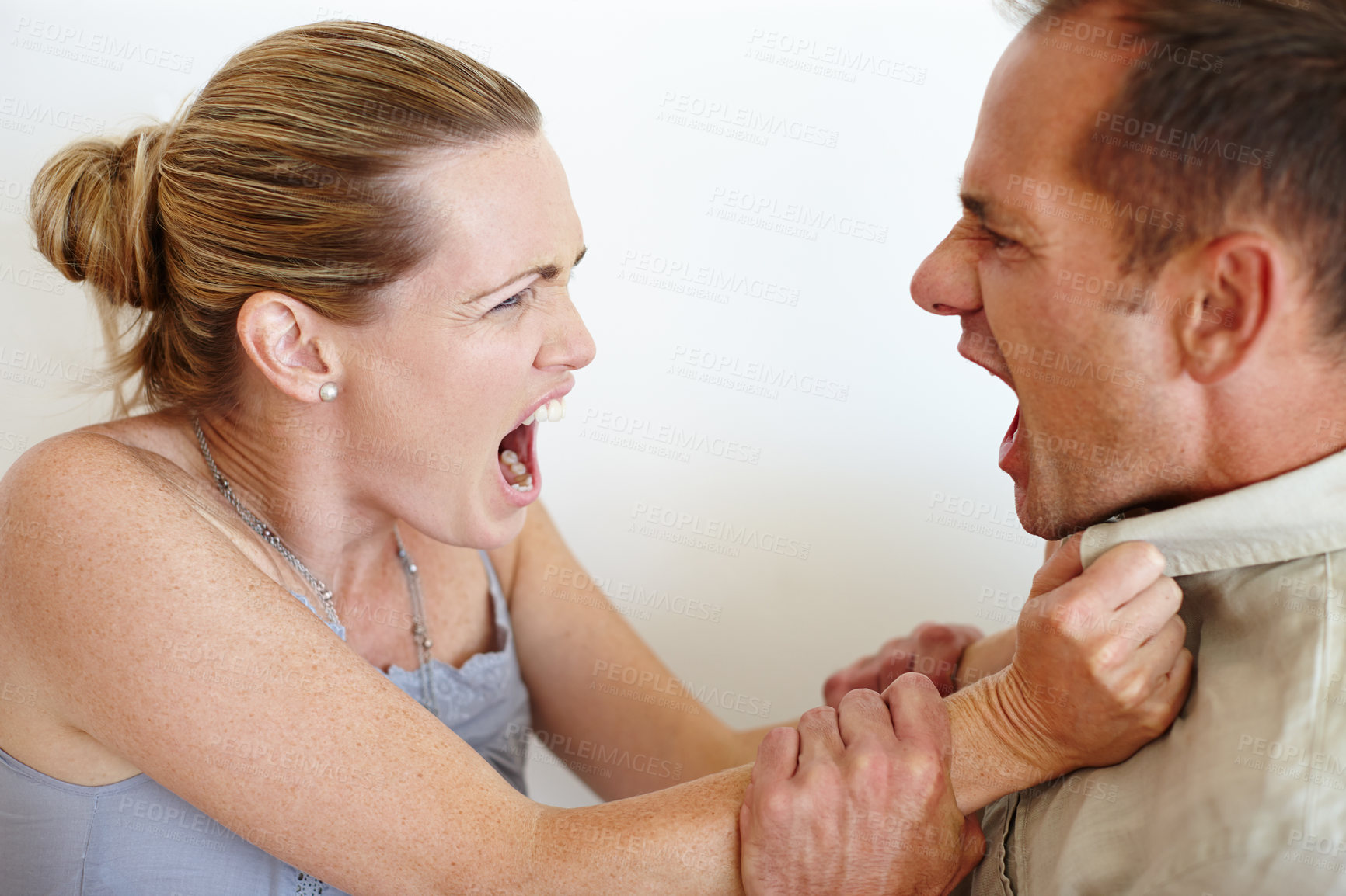 Buy stock photo Closeup of a wife grabbing her husband's shirt in anger as they fight