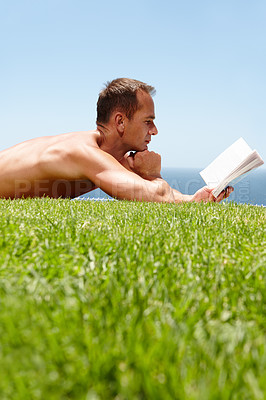 Buy stock photo Man, book and reading on lawn in summer by ocean with knowledge, relax and information on vacation. Person, thinking and novel on grass with ideas, topless and outdoor for holiday by sea in Naples