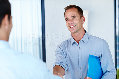 Buy stock photo Cropped shot of two men shaking hands in a corporate environment