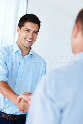 Buy stock photo Shot of a handsome young man shaking hands with a colleague in the office
