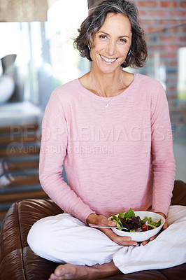 Buy stock photo Mature woman, sofa and smile with salad or vegetables for diet, nutrition and health at home. Female person, couch and happy in living room as vegetarian on break, relax and self care in portrait. 