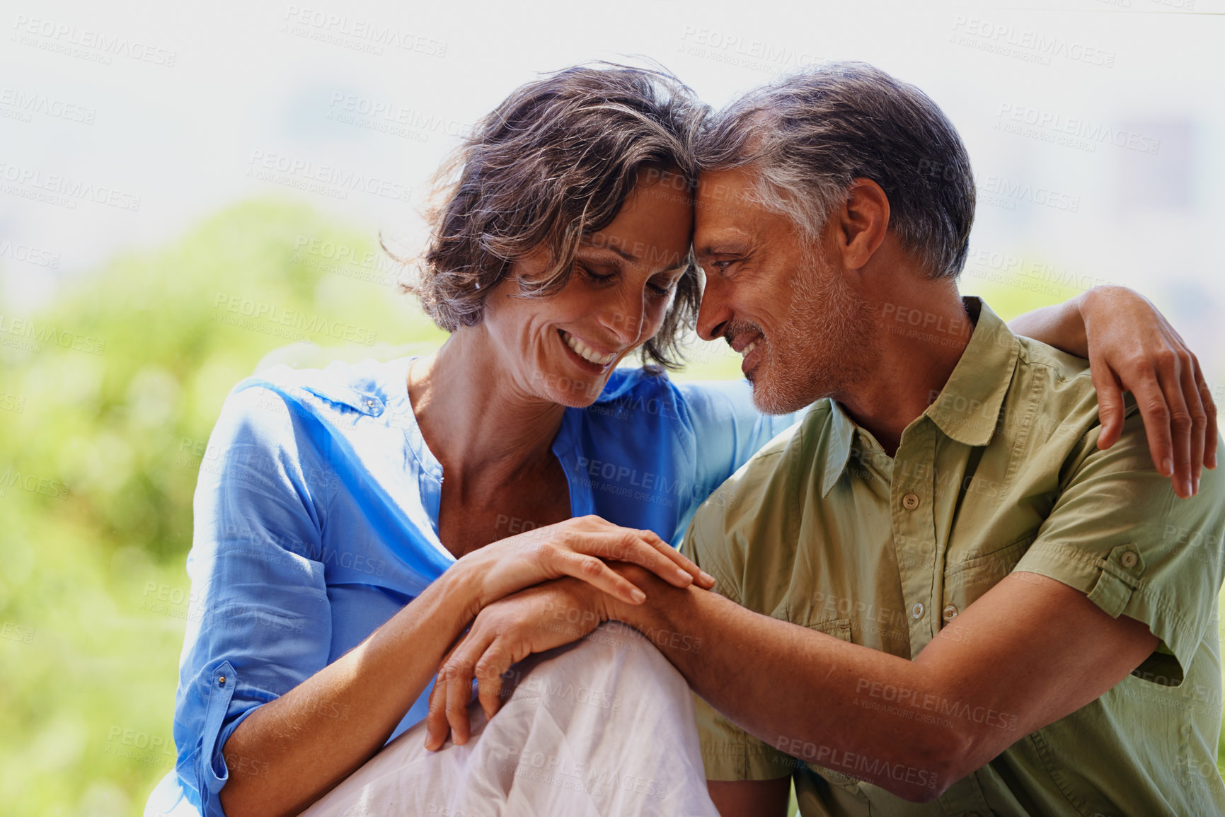 Buy stock photo A cropped shot of an affectionate mid adult couple sitting outdoors