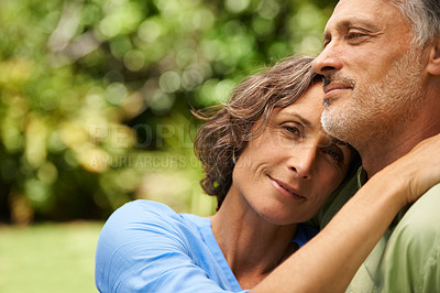 Buy stock photo A cropped portrait of a happy mid adult woman sitting affectionately with her husband outdoors