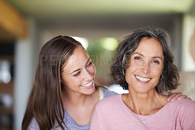 Buy stock photo A young woman smiling happily as she holds onto her mom