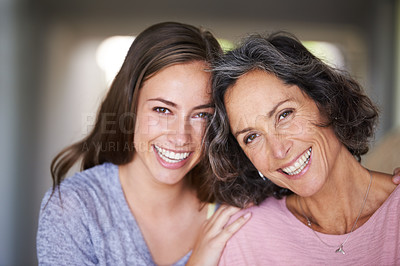 Buy stock photo A laughing mother and daughter standing in their home and looking at the camera