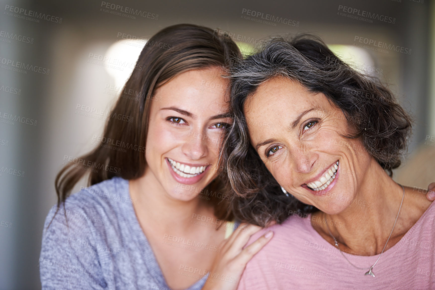 Buy stock photo A laughing mother and daughter standing in their home and looking at the camera