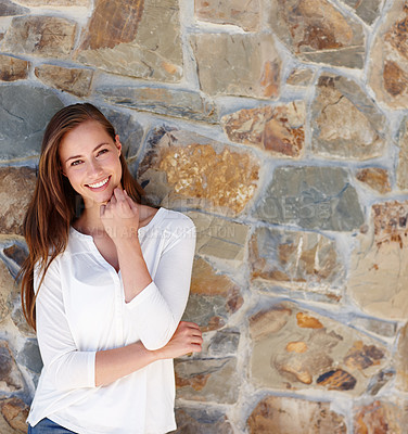 Buy stock photo Woman, portrait and smile by stone wall in home with confidence, relax or casual outfit on mockup space. Person, face and happy for holiday, vacation or peaceful getaway with shirt, good mood or calm