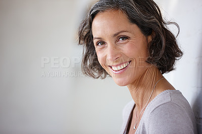 Buy stock photo Shot of an attractive mature woman leaning against a wall