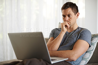 Buy stock photo Shot of a handsome young man using his laptop at home