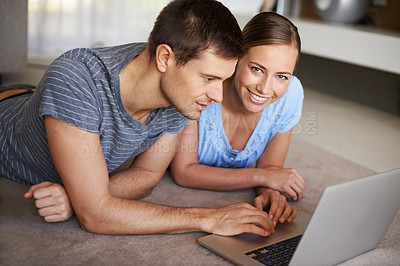 Buy stock photo Shot of a happy young couple using a laptop on the floor together