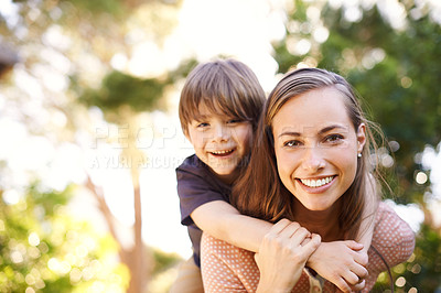 Buy stock photo Portrait of a happy young mother carrying her son on her back