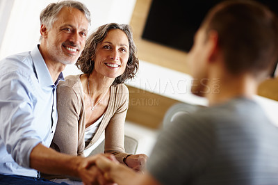 Buy stock photo Senior couple, smile and person with handshake for loan agreement, insurance policy and decision in living room. Man, woman and hand with gesture for deal, consultation and planning for retirement