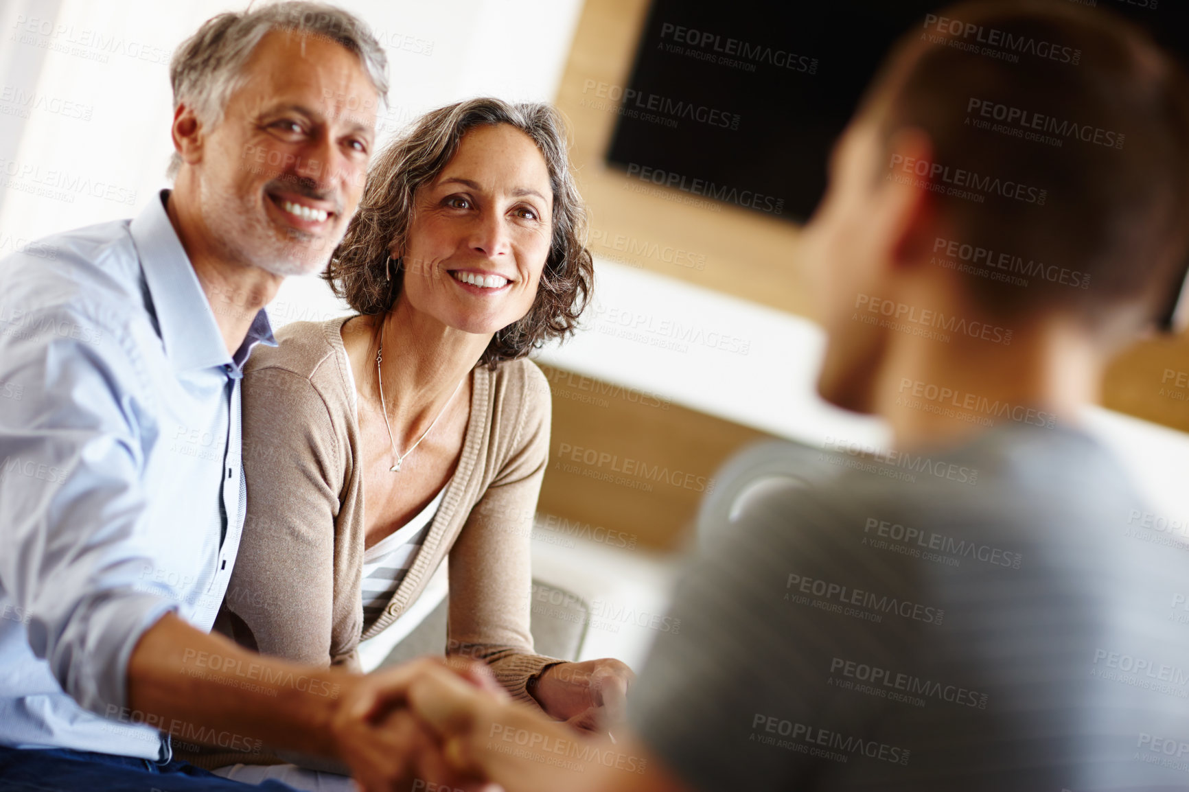 Buy stock photo Senior couple, smile and person with handshake for loan agreement, insurance policy and decision in living room. Man, woman and hand with gesture for deal, consultation and planning for retirement