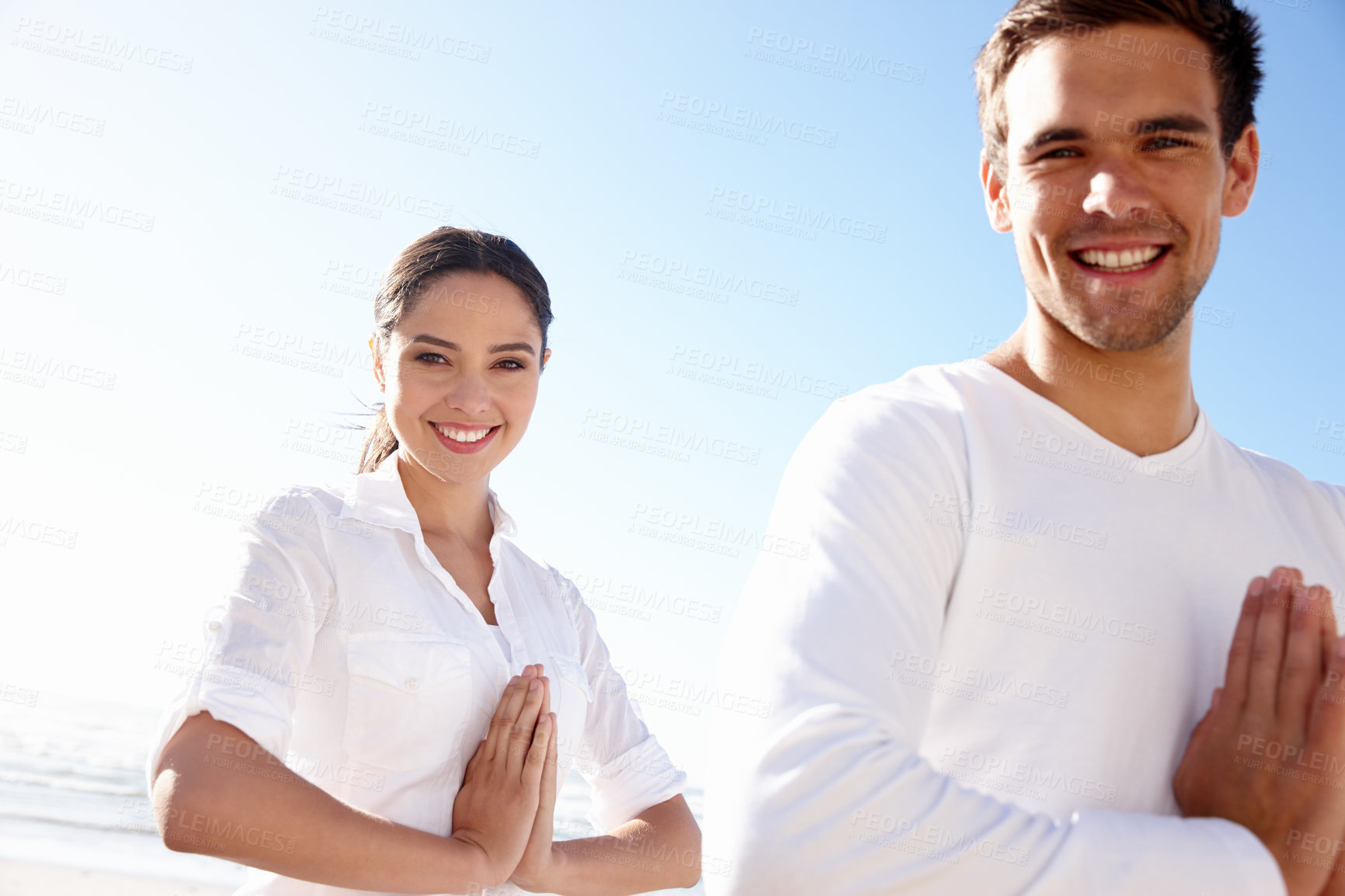 Buy stock photo Cropped shot of a young man and woman doing yoga beside the sea