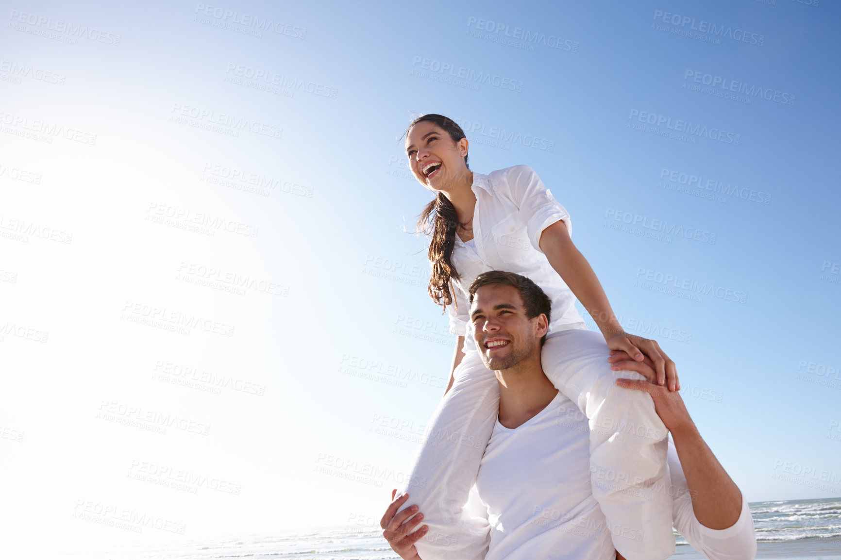 Buy stock photo Happy, couple and beach with piggyback and blue sky for valentines day, love or summer holiday together in embrace or outdoor romance. Man and woman with smile by ocean in nature on mockup space