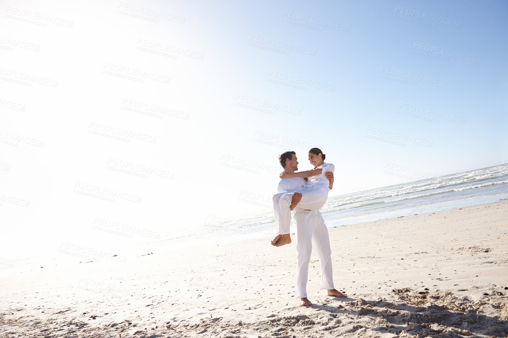 Buy stock photo Full length shot of a young man carrying his girlfriend along a beach