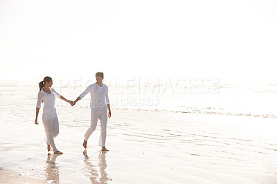 Buy stock photo Full length shot of an attractive young couple dressed in white walking along a beach