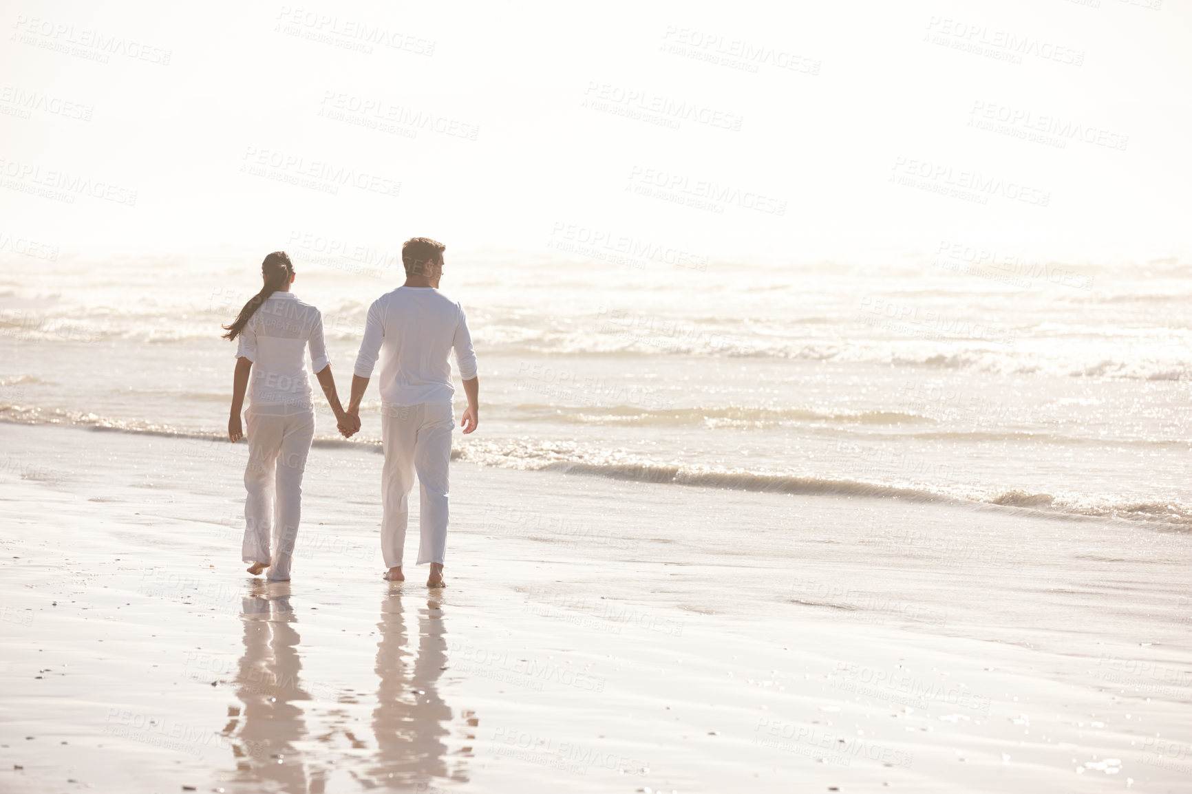 Buy stock photo Back view of couple, ocean and holding hands on beach, travel and commitment with trust and bonding outdoor. Love, care and support in relationship, honeymoon or anniversary with walking in nature