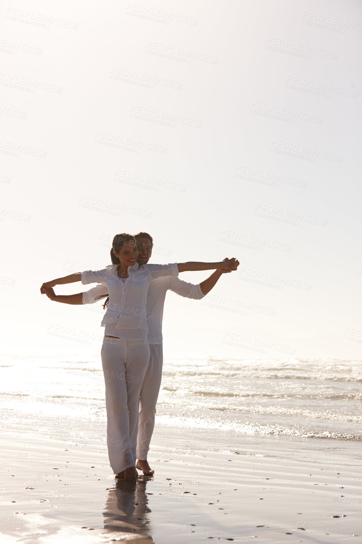 Buy stock photo Full length shot of an attractive young couple dressed in white walking along a beach