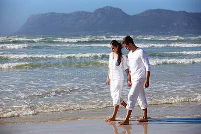 Buy stock photo Couple, holding hands and walking with love on beach for bonding, care or support in nature. Man and woman enjoying stroll by the ocean waves or coast for holiday, weekend or outdoor trip by the sea