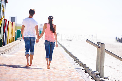 Buy stock photo Back view, couple holding hands and walking on beach, romantic date and commitment with trust. Love, care and people together outdoor for anniversary, bonding and relax by sea with partner for travel