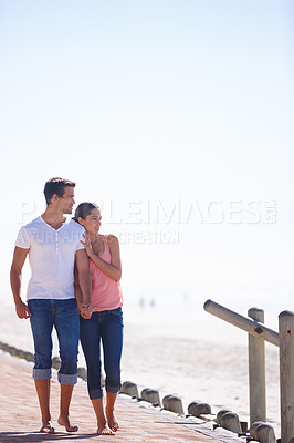 Buy stock photo Full length shot of an attractive young couple walking beside the sea