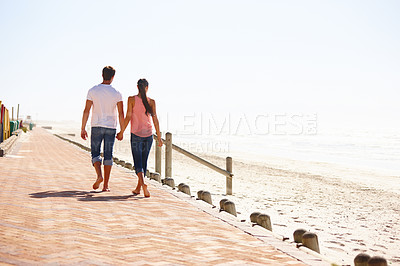 Buy stock photo Man, woman and holding hands for walk on beach, back view of romantic date and commitment with trust. Love, care and people together outdoor for anniversary, bonding and ocean with partner for travel