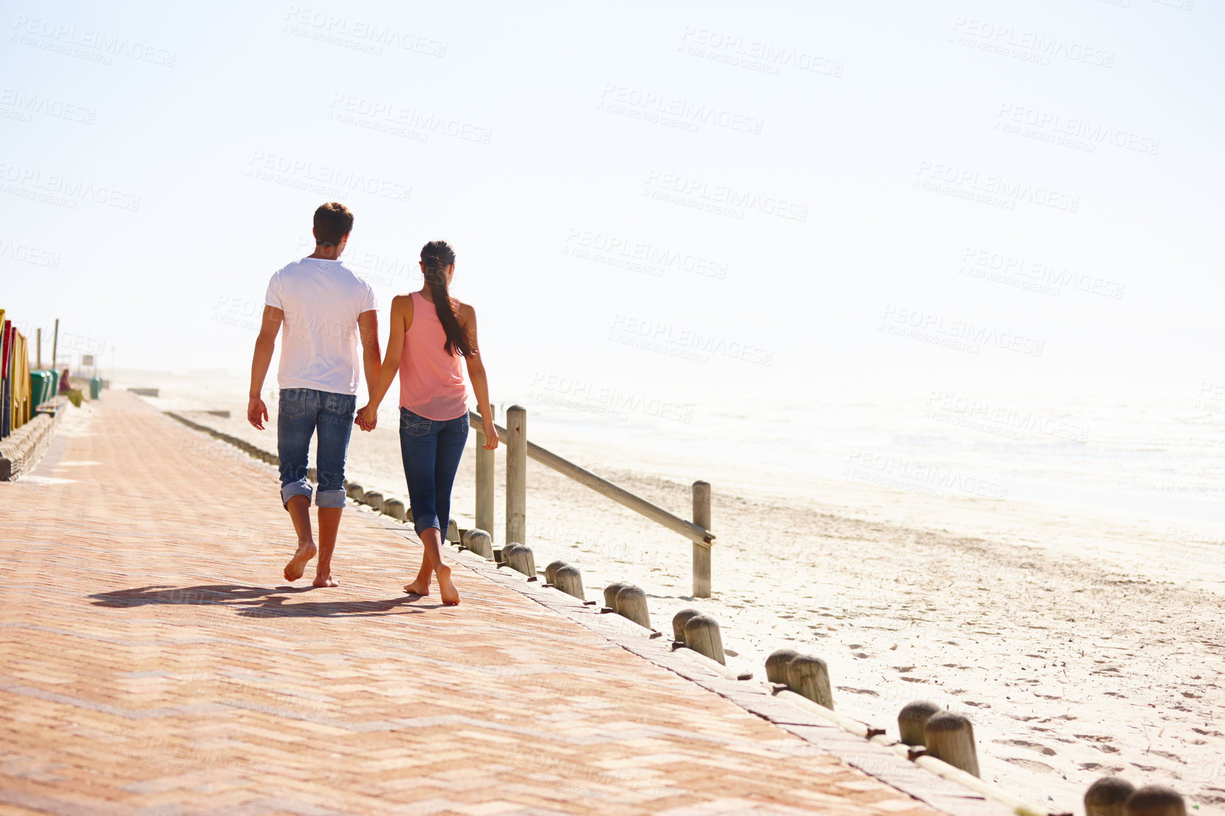 Buy stock photo Man, woman and holding hands for walk on beach, back view of romantic date and commitment with trust. Love, care and people together outdoor for anniversary, bonding and ocean with partner for travel