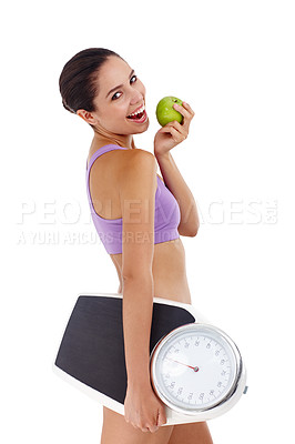 Buy stock photo Studio shot of an attractive young woman dressed in gym clothes holding an apple and weight scale