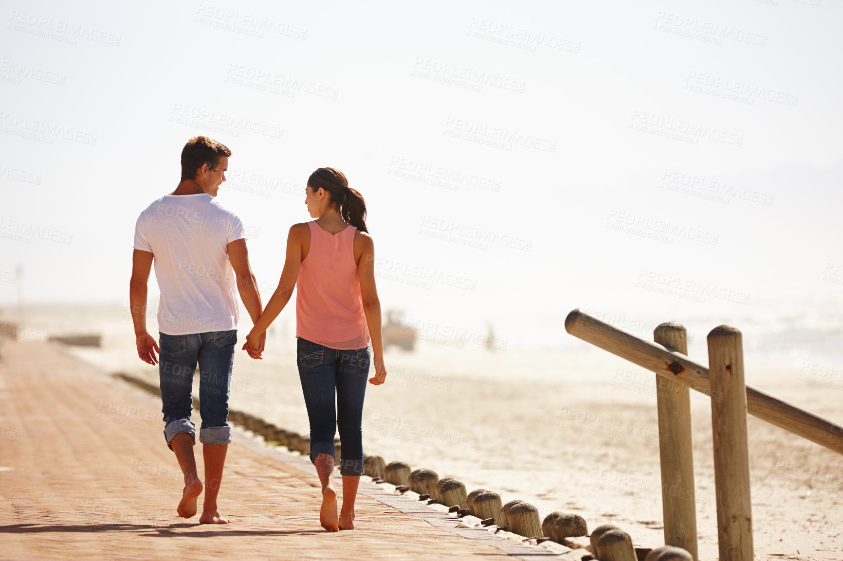 Buy stock photo Man, woman and holding hands for walk by the ocean, back view of romantic date and commitment with trust. Love, care and people outdoor for anniversary, bonding at beach with partner and travel