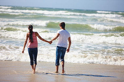 Buy stock photo Couple, holding hands and beach with back for love, support or care together on outdoor holiday. Rear view of man and woman enjoying fun walk or playing on the ocean coast, water or bonding in nature