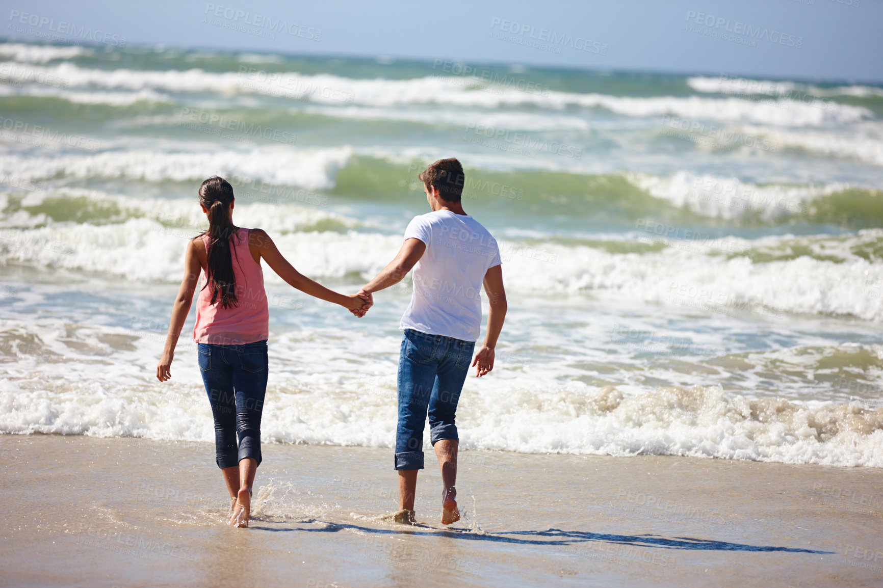 Buy stock photo Couple, holding hands and beach with back for love, support or care together on outdoor holiday. Rear view of man and woman enjoying fun walk or playing on the ocean coast, water or bonding in nature