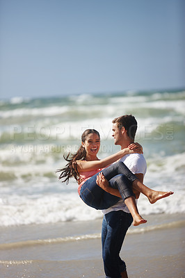 Buy stock photo Shot of a happy young couple being playful on the beach