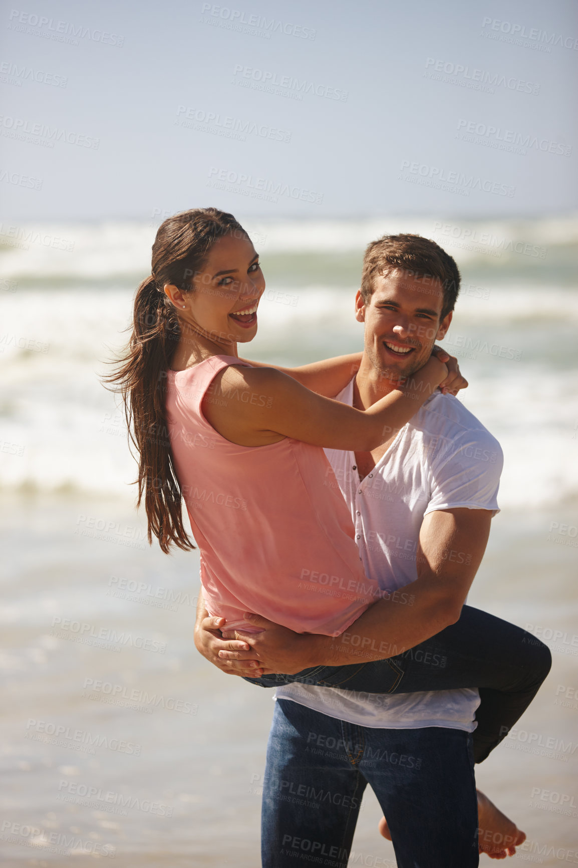 Buy stock photo Shot of a young couple being playful on the beach