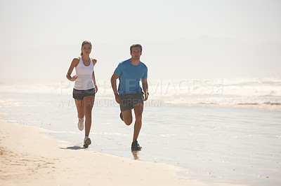 Buy stock photo Shot of a young couple jogging together on the beach