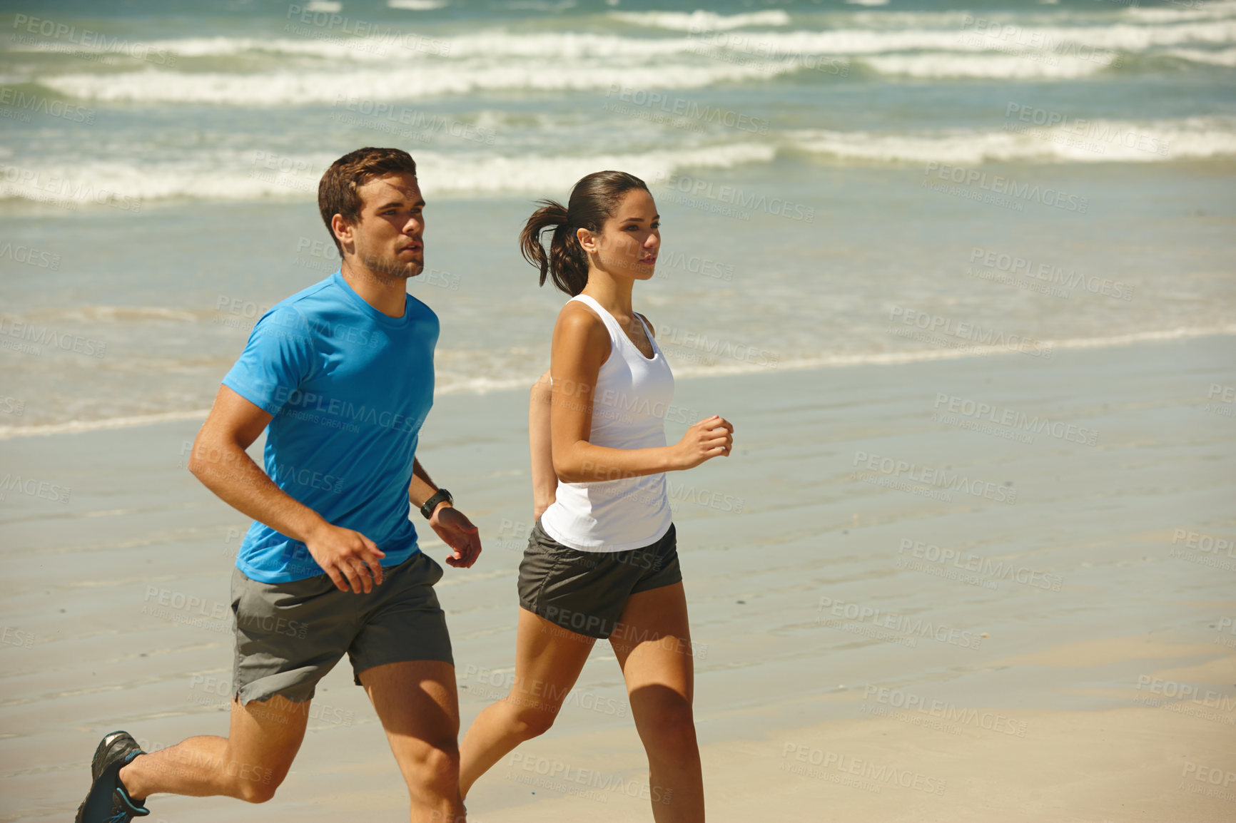 Buy stock photo Shot of a young couple jogging together on the beach