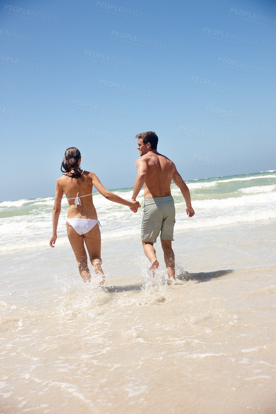 Buy stock photo Couple, rear view and holding hands in water with travel for bonding, summer vacation and anniversary getaway. Man, woman and love by ocean with swimwear for walking, healthy relationship or blue sky